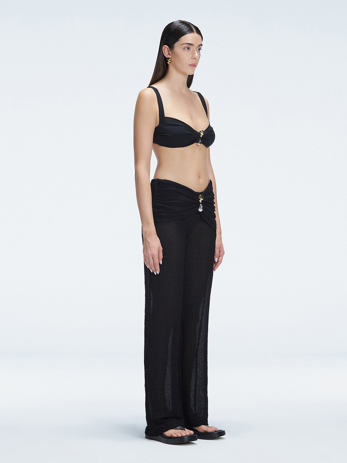 Side view of model showcasing the high-rise fit and gold hoop detail on the Angelique Black Pants.
