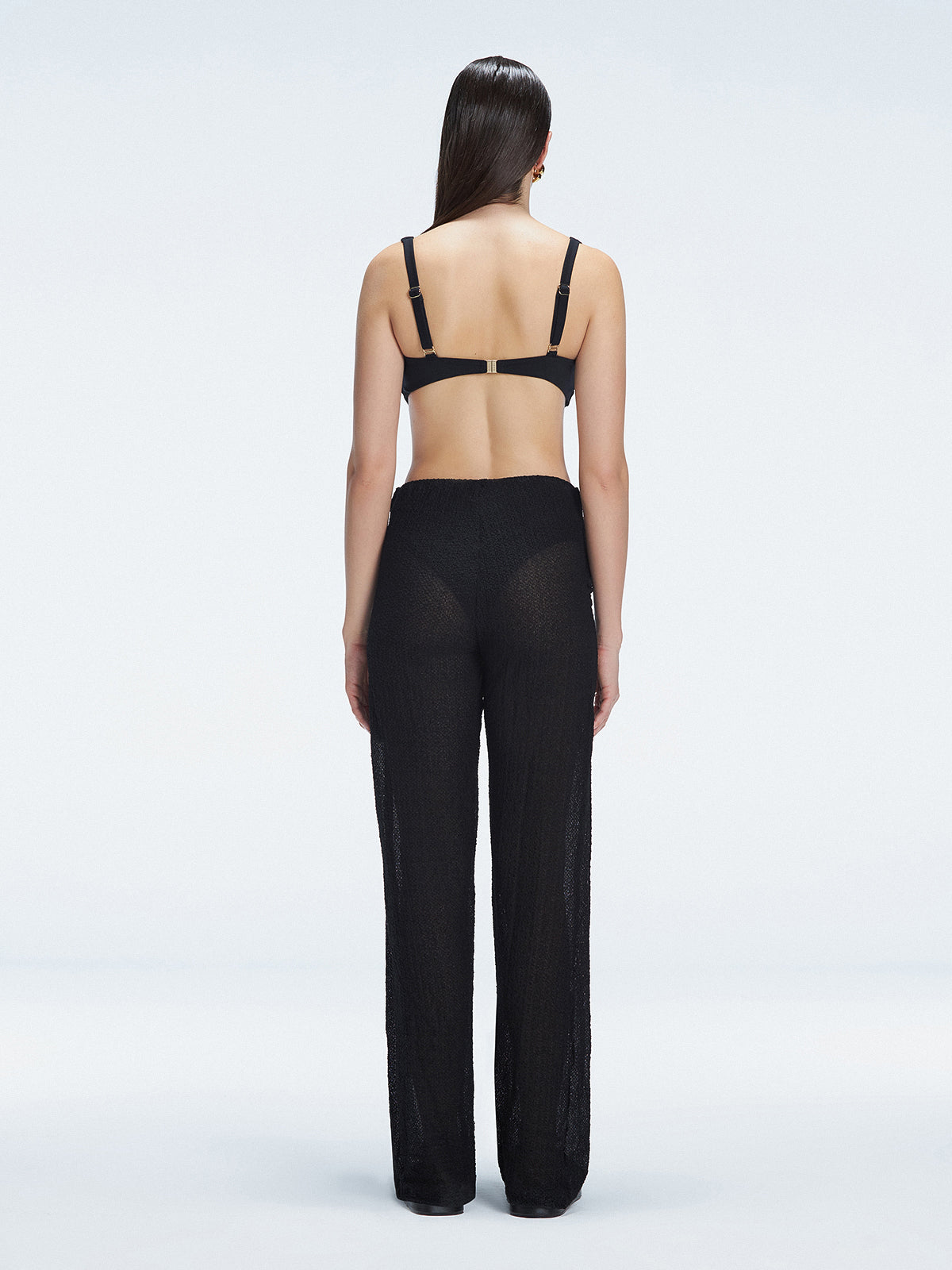 Back view of model wearing Angelique Black Pants, highlighting the layered panel and sleek silhouette.
