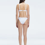 Back view of model wearing Emilia White Bikini Bottom, highlighting the moderate coverage and chic fit.
