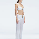 Side view of model showcasing the high-rise fit and gold hoop detail on the Angelique White Pants.
