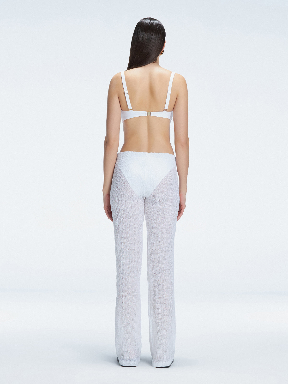 Back view of model wearing Angelique White Pants, highlighting the layered panel and sleek silhouette.
