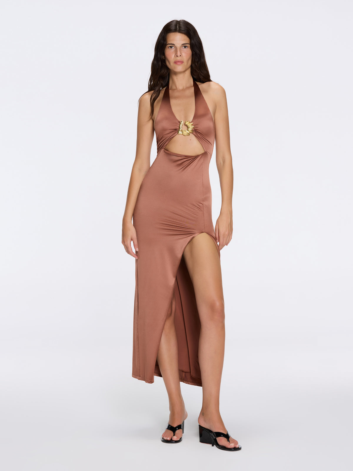 Woman wearing a brown halter neck dress with a cutout design on a white background