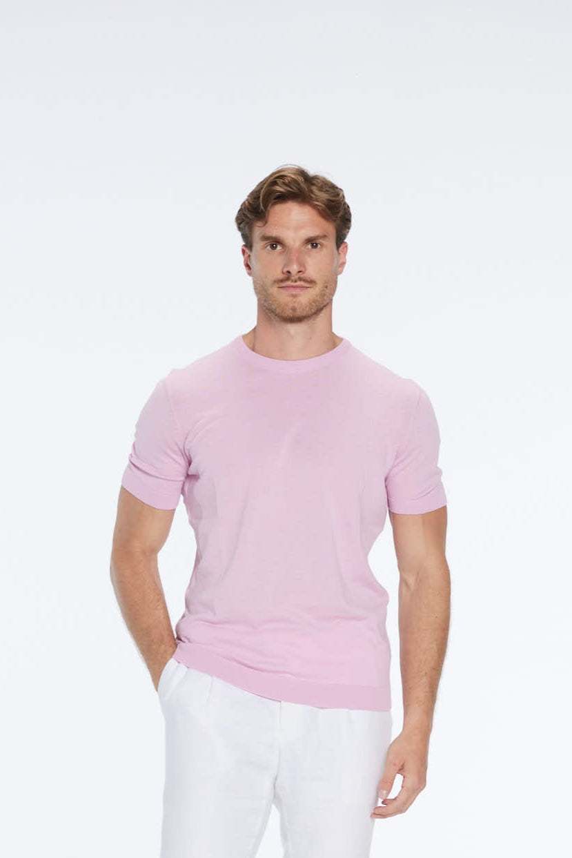 Man wearing a pink short-sleeve shirt and white pants on a white background