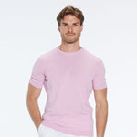 Man wearing a pink short-sleeve shirt and white pants on a white background