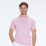 Man wearing a pink short-sleeve shirt and white pants on a white background