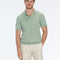 Man wearing a green polo shirt and beige shorts on a white background