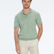 Man wearing a green polo shirt and beige shorts on a white background