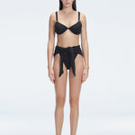 "Model wearing the Dylan Black Bikini Bottom with a high-leg silhouette, showcasing its sleek design by the pool."
