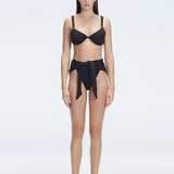 "Model wearing the Dylan Black Bikini Bottom with a high-leg silhouette, showcasing its sleek design by the pool."
