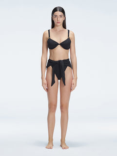 "Model wearing the Dylan Black Bikini Bottom with a high-leg silhouette, showcasing its sleek design by the pool."
