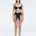 "Model wearing the Dylan Black Bikini Bottom with a high-leg silhouette, showcasing its sleek design by the pool."
