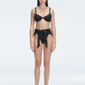 "Model wearing the Dylan Black Bikini Bottom with a high-leg silhouette, showcasing its sleek design by the pool."
