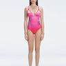 Front view of model wearing Marina Degraded Red-Pink One Piece swimsuit with halter neck and ruched waist detail.
