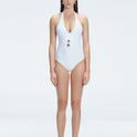 Front view of model wearing Miley White One Piece swimsuit with halter neck and twisted gold accessory.
