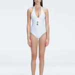 Front view of model wearing Miley White One Piece swimsuit with halter neck and twisted gold accessory.
