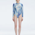 Front view of model wearing Mireya Blue Optical Bodysuit with long sleeves and bold optical print.
