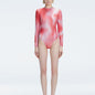 Front view of model wearing Mireya Red Optical Bodysuit with long sleeves and bold optical print.
