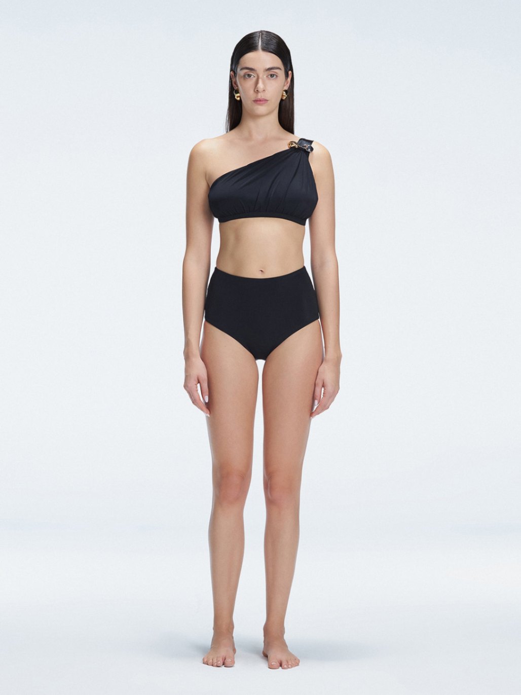 "Model wearing the Romina Black High-Waist Bikini Top with matte satin contrast and moderate coverage, standing poolside."
