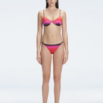 Front view of model wearing Rory Pink Optical Bikini Bottom with low-rise fit and adjustable side ties.
