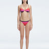 Front view of model wearing Rory Pink Optical Bikini Bottom with low-rise fit and adjustable side ties.
