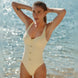 Model wearing the Elba White Dress with a V-neckline and fringe details, posing by a serene lakeside.
