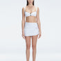 Front view of model wearing Siena White Mini Skirt with buckle detail and two-layered design.
