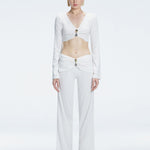 Front view of model wearing Helena White Pants with mid-rise V-shaped waistline, wide-legged cut, and buckle detail.
