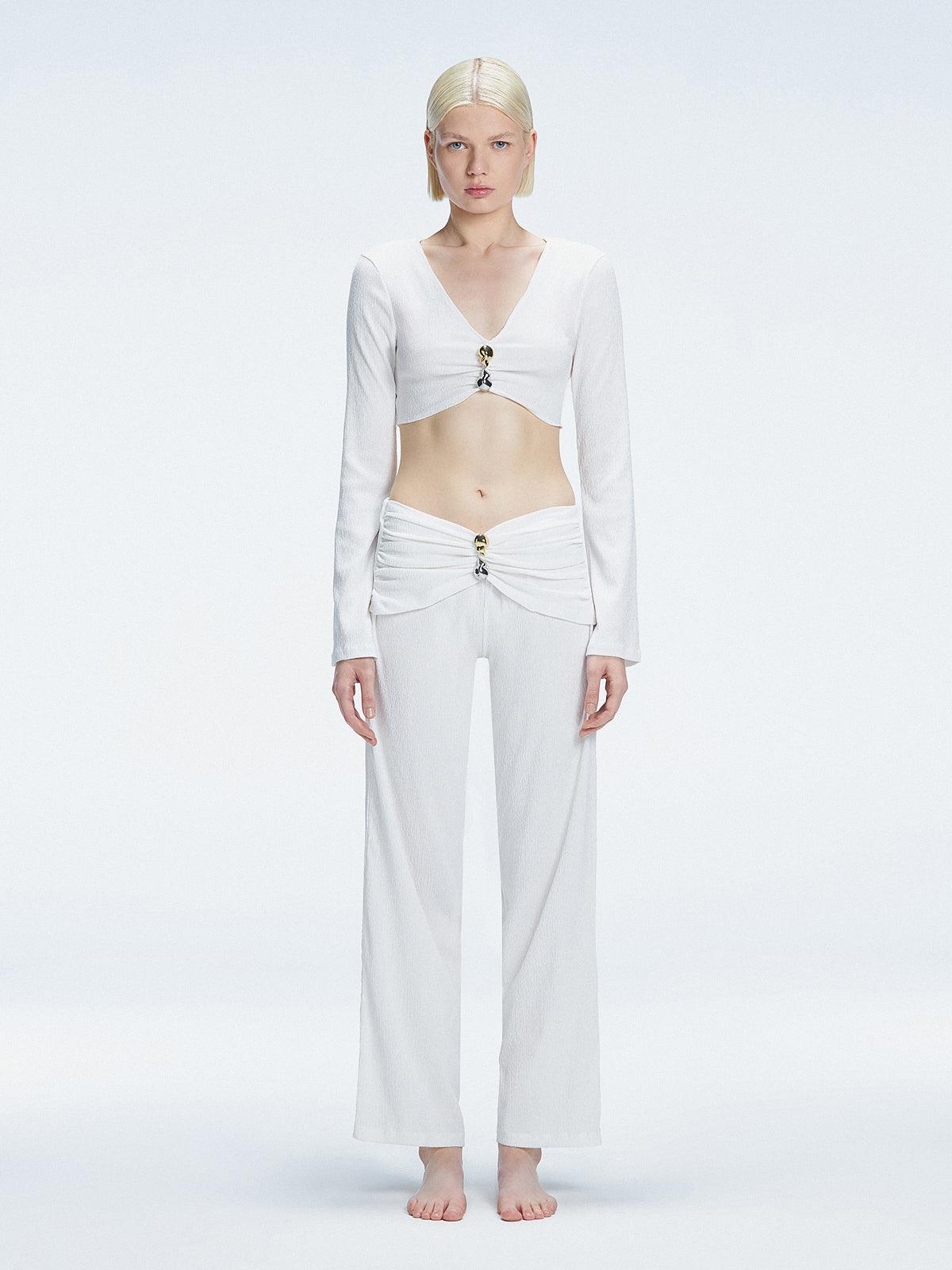 Front view of model wearing Helena White Pants with mid-rise V-shaped waistline, wide-legged cut, and buckle detail.
