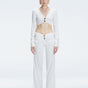 Front view of model wearing Helena White Pants with mid-rise V-shaped waistline, wide-legged cut, and buckle detail.
