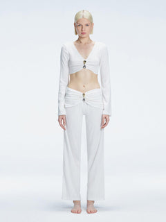 Front view of model wearing  Sirenia White Crop Top and Helena Pants   with V-neck, long sleeves, and buckle detail.
