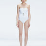 Front view of model wearing Ursula White One Piece swimsuit with strapless silhouette and twisted gold accessory.
