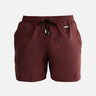  A collage of the Louis Bordeaux mid-thigh length men's swim shorts from various angles. The front view emphasizes the elastic waistband, drawstring with black nickel stoppers, and Moeva patch. The back view showcases the rich bordeaux color and sleek design. The side view highlights the two open side pockets and tailored fit, hinting at the fabric's lightness and quick-dry properties. A close-up focuses on the fabric texture, drawstring details, and craftsmanship. The collage collectively illustrates the s