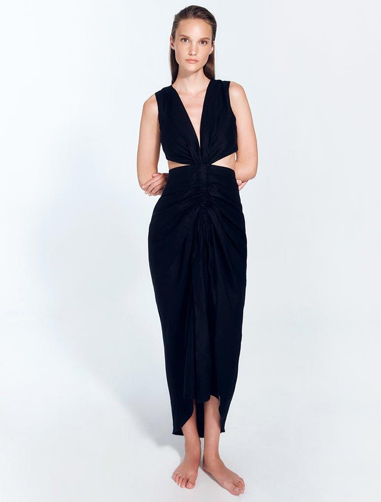 " Front view of Adelice black dress with a deep V neckline, center ruching, asymmetrical skirt, high front slit, and side cutouts."