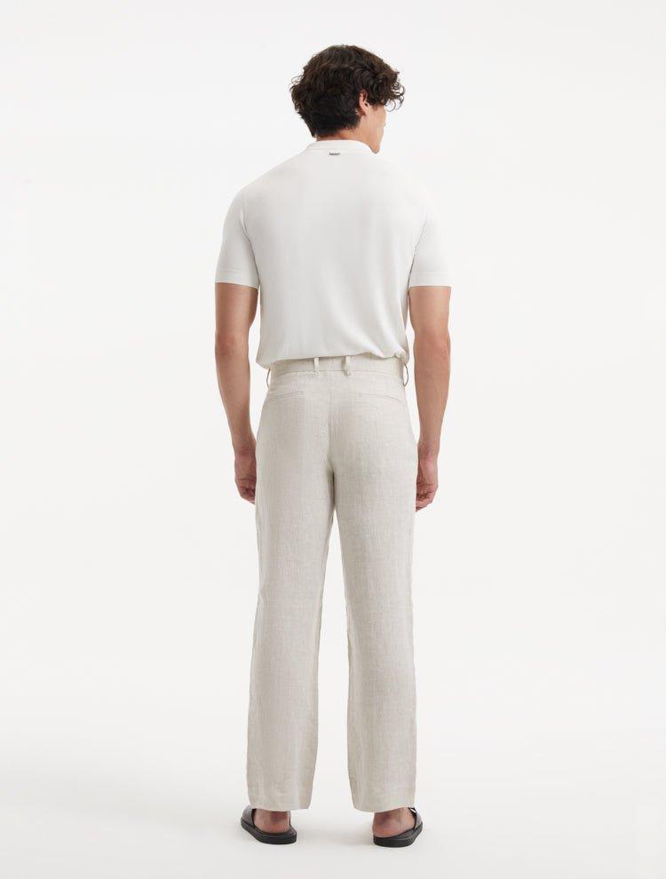 Model wearing Adrian Beige Pants from the back view, highlighting the sleek and streamlined design with practical welt pockets and modern button detailing.