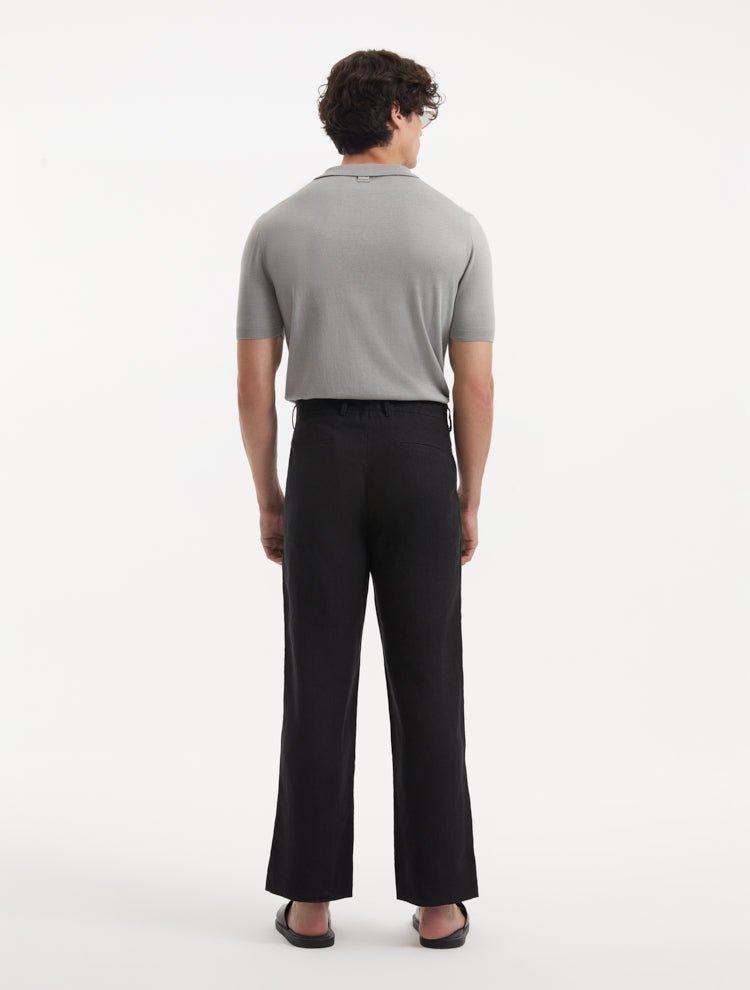 Model in Adrian Black Pants from the back, emphasizing the elegant straight cut and the stylish ankle-length design. The sophisticated black color and button detailing add a contemporary touch.