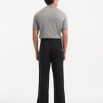 Model in Adrian Black Pants from the back, emphasizing the elegant straight cut and the stylish ankle-length design. The sophisticated black color and button detailing add a contemporary touch.