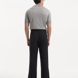 Model in Adrian Black Pants from the back, emphasizing the elegant straight cut and the stylish ankle-length design. The sophisticated black color and button detailing add a contemporary touch.