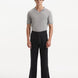 Model wearing Adrian Black Pants from the front, showcasing the relaxed fit and straight cut. The pants feature a mid-rise waist, button detailing, and practical welt pockets, paired with sleek dress shoes.