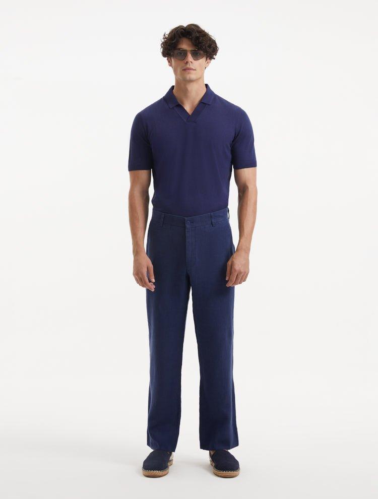 Model wearing Adrian Dark Blue Pants from the front, highlighting the relaxed fit and straight cut. The pants feature a mid-rise waist, unique button detailing, and welt pockets, styled with dress shoes.