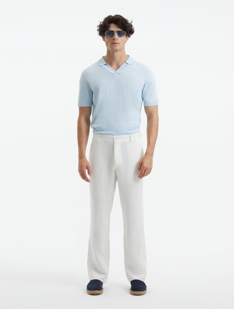 Model showcasing Adrian White Pants from the front, highlighting the relaxed fit, mid-rise waist, and straight cut. The pants feature welt pockets and subtle button detailing for a contemporary touch.