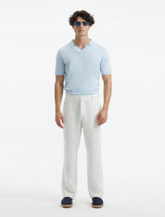 Model showcasing Adrian White Pants from the front, highlighting the relaxed fit, mid-rise waist, and straight cut. The pants feature welt pockets and subtle button detailing for a contemporary touch.