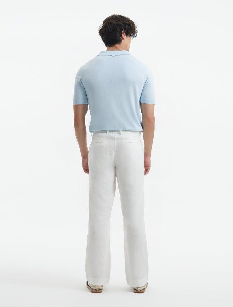 Model displaying Adrian White Pants from the back, focusing on the clean lines and relaxed fit. The mid-rise waist and practical welt pockets are clearly shown, enhancing the pants’ refined look.