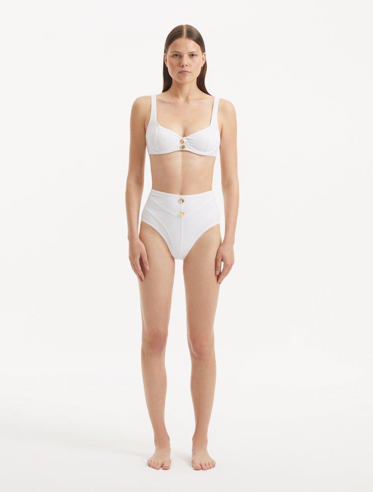 Model wearing the Adva White Bikini Bottom, showcasing the high-waist design and shell accents.