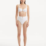 Model wearing the Adva White Bikini Bottom, showcasing the high-waist design and shell accents.
