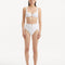 Model wearing the Adva White Bikini Bottom, showcasing the high-waist design and shell accents.