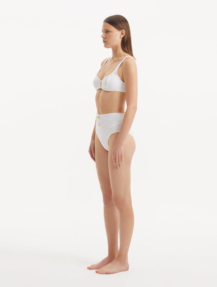 Side angle of the Adva White Bikini Bottom, highlighting the intricate button details and contemporary design.