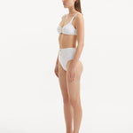 Side angle of the Adva White Bikini Bottom, highlighting the intricate button details and contemporary design.
