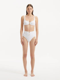 Model wearing the Adva White Bikini Set, showcasing gold shell-shaped accents.

