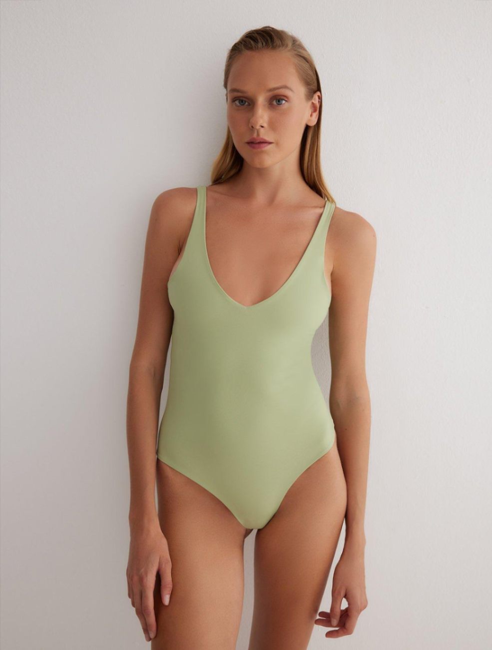 "Front view of Agneta Green/Nude Reversible Bodysuit highlighting its modern design and moderate coverage."