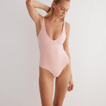 "Model wearing the Agneta Orange/Pink reversible bodysuit from the front, showcasing its modern design with a scoop neckline and body-hugging fit. "